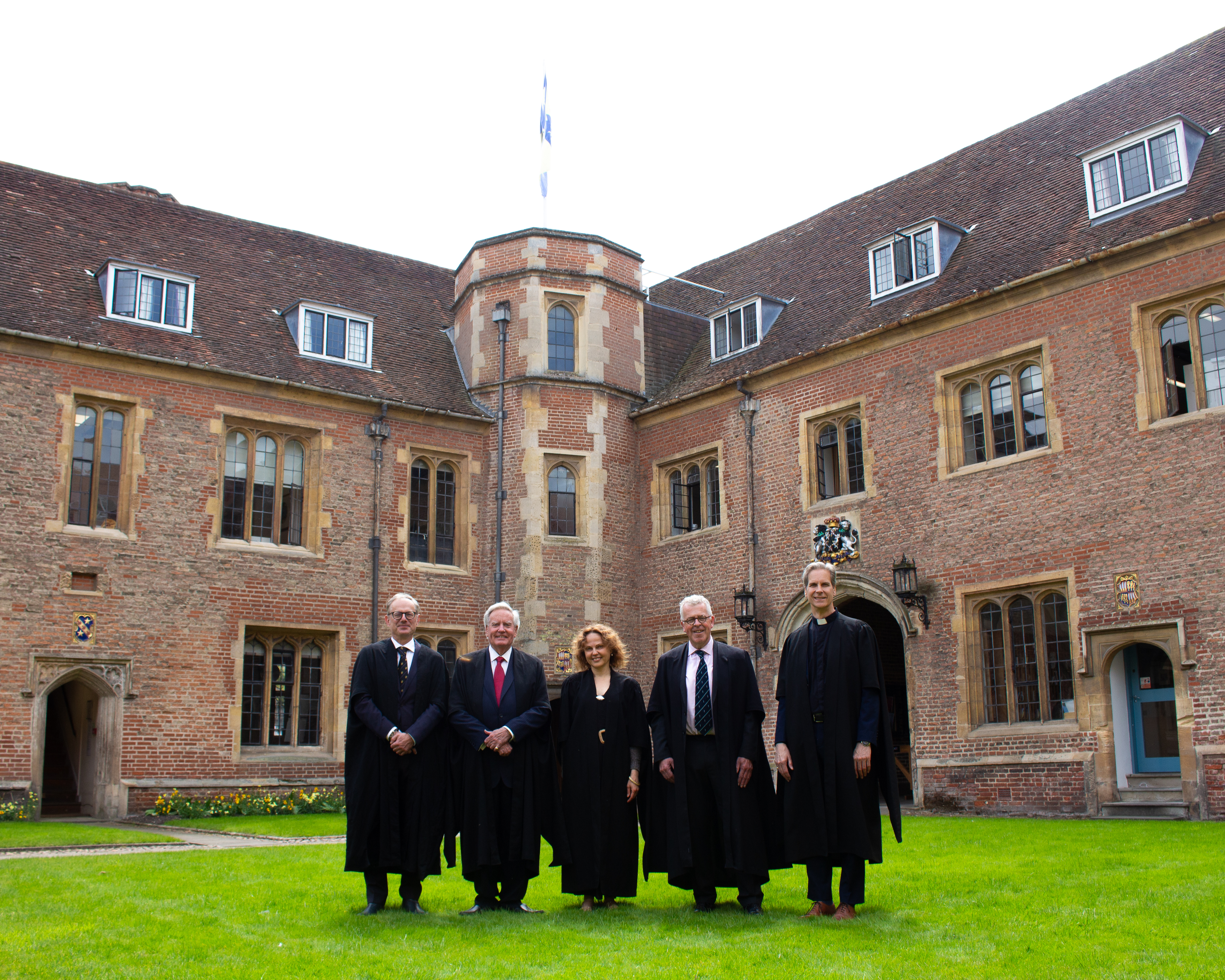 Fellows lined up in Magdalene's First Court in front of the College flag. 