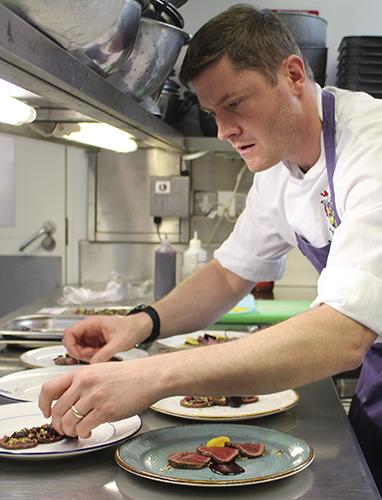 Chef working in the Magdalene kitchen plating up food.